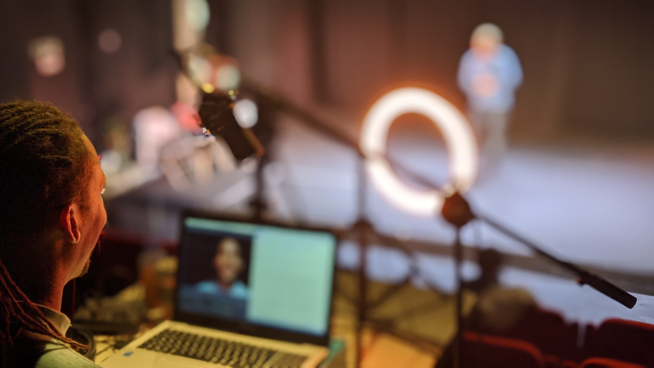 A technician sits behind a laptop whilst filming a performance