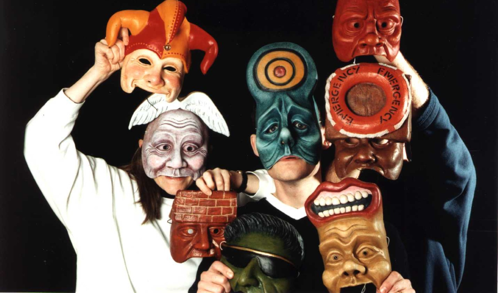 Three actors wearing and holding the fragment masks