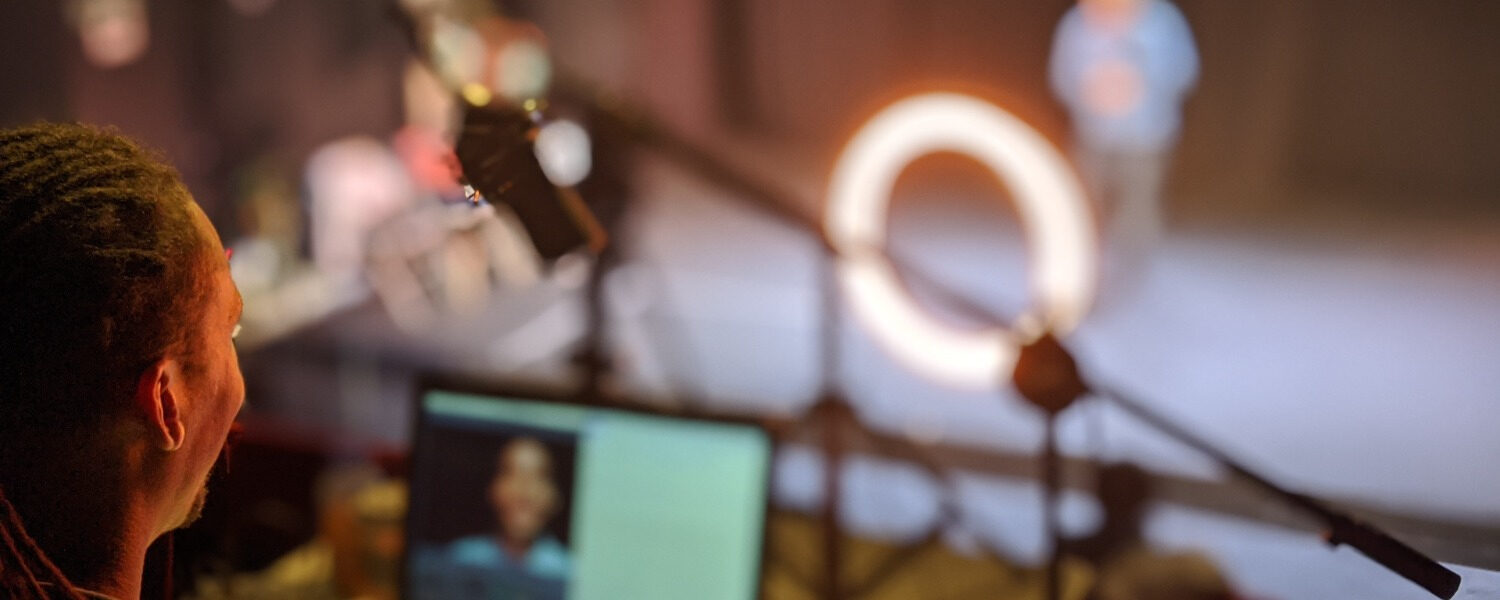 A technician sits behind a laptop whilst filming a performance