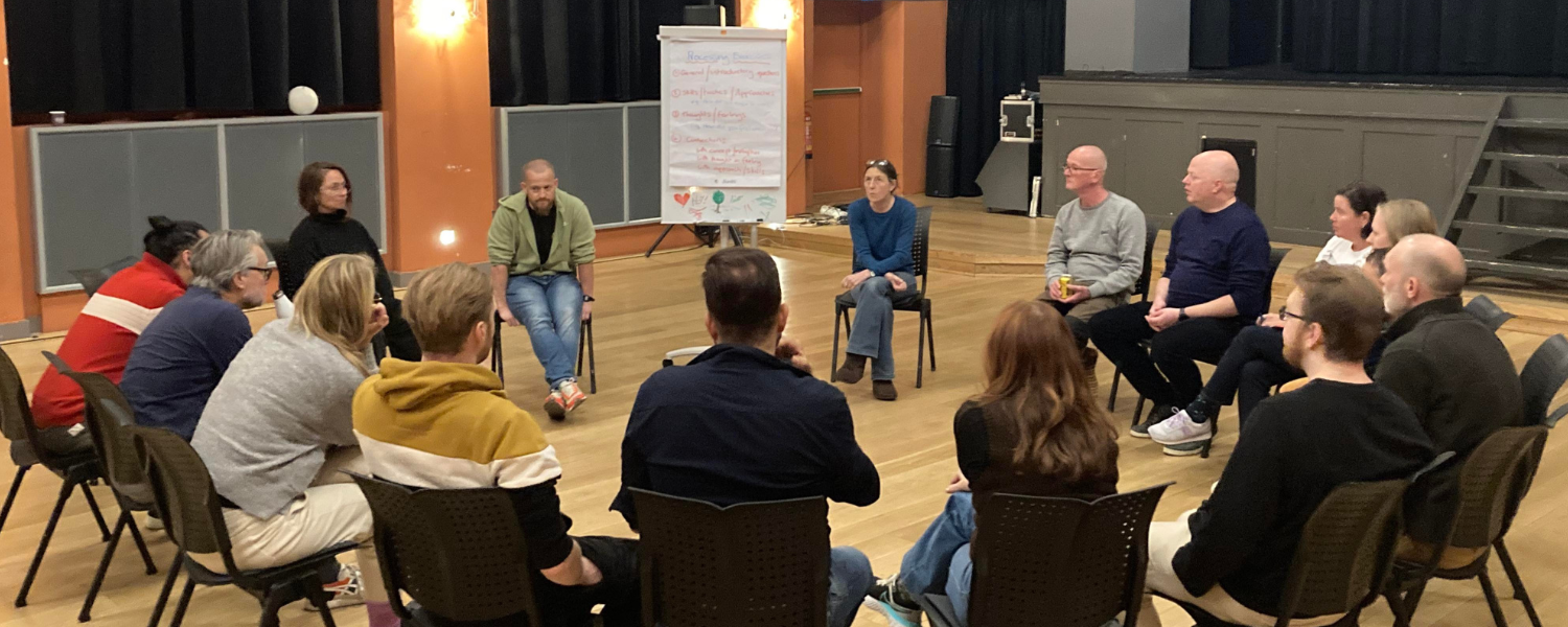 Lou and Dave delivering to a group sat in a circle of chairs